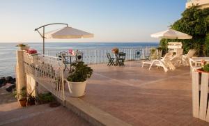 a patio with chairs and an umbrella and the ocean at Appartamento in Villa Agnese in Acitrezza