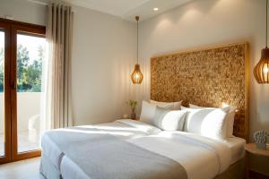 una camera da letto con un grande letto bianco e una finestra di S & O Villas Corfu a Dassia