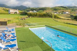 uma piscina com cadeiras e pessoas a nadar nela em Casa de Campo, Algarvia em Algarvia