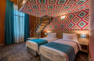 two beds in a room with a colorful ceiling at Gladius Inn Boutique Hotel by DNT Group in Tbilisi City