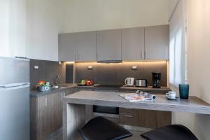 a kitchen with white cabinets and a counter with chairs at Rose Central Master Bedroom Apartment in Rhodes Town