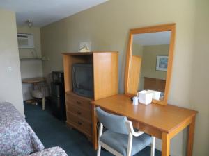 Cette chambre comprend un bureau, une télévision et un miroir. dans l'établissement Country Lodge, à Florida City