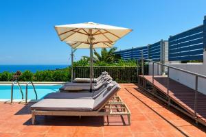 - deux chaises longues avec un parasol à côté de la piscine dans l'établissement Aries Villas, à Skiathos Chora