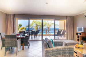 een woonkamer met een tafel en stoelen en een balkon bij Oceanfront Apartment Yellow Tail Snapper at Den Laman in Kralendijk