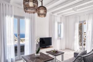 a living room with white walls and windows and a television at Katikies Villas Mykonos in Elia Beach