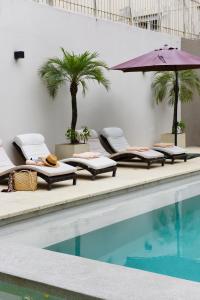a swimming pool with lounge chairs and an umbrella at Argenta Suites Belgrano in Buenos Aires