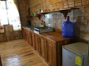 a kitchen with wooden cabinets and a blue bottle on the counter at Suki Cafe Apartments in Canoa