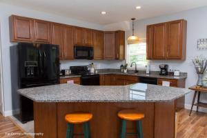 a kitchen with wooden cabinets and a island with bar stools at Mama Bears Blue Bungalow in Asheville