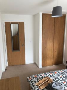 a bedroom with a bed and a wooden door at Quayside Apartment in Cardiff Bay in Cardiff