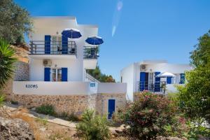 a white building with blue doors and umbrellas at John Akroyiali in Loutro