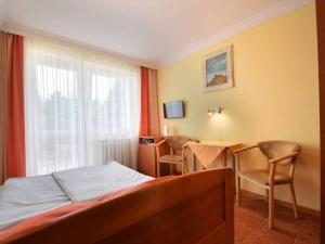 a bedroom with a bed and a table with chairs at Pensjonat Anker pokoje in Ustronie Morskie