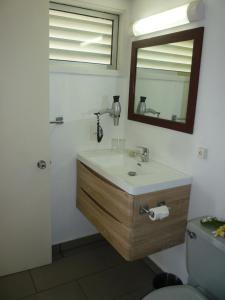 y baño con lavabo, espejo y aseo. en Royal Tahitien en Papeete