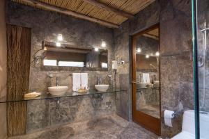 uma casa de banho com 2 lavatórios e uma cabina de duche em vidro. em Hotel Cumbres San Pedro de Atacama em San Pedro de Atacama
