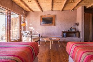 1 dormitorio con 2 camas, mesa y sofá en Hotel Cumbres San Pedro de Atacama, en San Pedro de Atacama