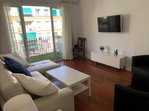 a living room with a white couch and a table at Apartamento Malagueta 1 Linea playa centro Malaga in Málaga