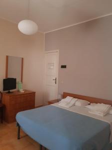 sypialnia z niebieskim łóżkiem i telewizorem w obiekcie HOTEL TERME MARINO w mieście Ali Terme