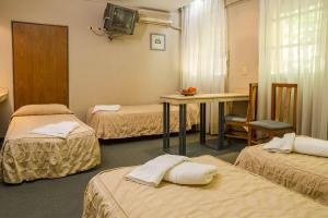 Habitación con 3 camas, mesa y TV. en Hotel Cordon Del Plata en Mendoza