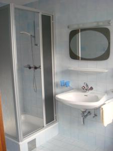 ein Bad mit einer Dusche, einem Waschbecken und einem Spiegel in der Unterkunft Haus Anton Schranz in Sankt Anton am Arlberg