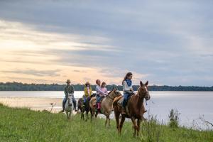 a group of people riding horses on the beach at Puerto Valle Hotel de Esteros in Puerto Valle