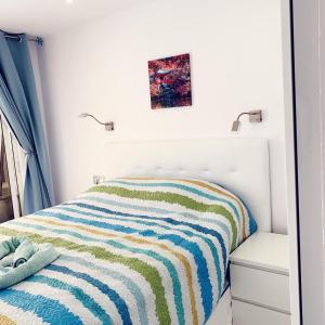 プラヤ・デル・クーラにあるMonseñor Apartmentのベッドルーム1室(ストライプ毛布付きのベッド1台付)