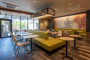 a restaurant with tables and chairs and windows at Shizutetsu Hotel Prezio Kyoto Karasumaoike in Kyoto