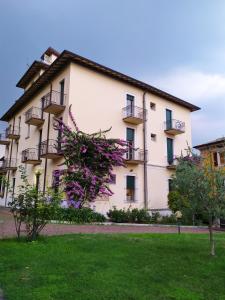 ein großes weißes Gebäude mit Balkonen darauf in der Unterkunft Ostello delle cartiere in Toscolano-Maderno