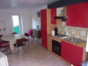 uma cozinha com armários vermelhos, uma mesa e um lavatório em triplex douillet em Largentière