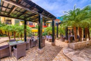 patio ze stołami, krzesłami i palmami w obiekcie Wayak Hotel w mieście Managua