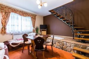 a living room with a table and chairs and a spiral staircase at Willa Cetynka in Zakopane