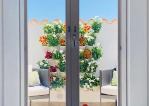 a display of flowers on a window with two chairs at Alma White Suite in Siracusa