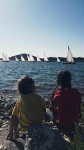 two women sitting on the beach with sailboats in the water at Apartments Leonarda in Murter