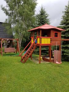un parque infantil con una casa de juegos y un tobogán en Miś Pokoje Gościnne, en Bukowina Tatrzańska