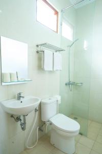 a white bathroom with a toilet and a sink at Diana Hotel Jogja in Yogyakarta