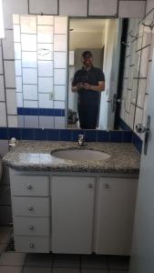 a man taking a picture of a bathroom sink at Apartamento Caldas in Caldas Novas