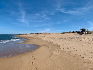 einen Strand mit Fußabdrücken im Sand und im Ozean in der Unterkunft Primafila in Sauce de Portezuelo