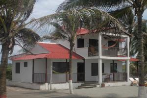 a white house with a red roof and palm trees at Hotel Mar del Viento in San Bernardo del Viento