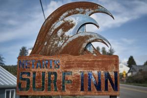 a sign for a restaurant with aries surfin sign at Netarts Surf Inn in Tillamook