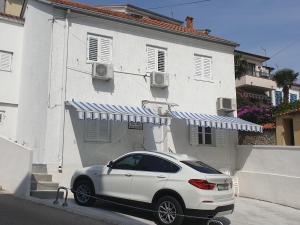 une voiture blanche garée devant une maison blanche dans l'établissement Villa Mely CRIKVENICA KVARNER, à Crikvenica