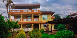 a yellow and orange house with bushes in front of it at Shimbwe Meadows Guest House in Moshi