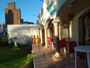 a patio with red chairs and a table and a building at Hotel Gala in Villa Carlos Paz