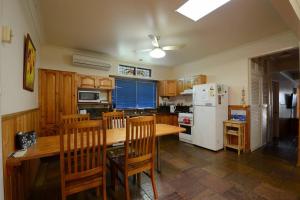 a kitchen with a wooden table and a white refrigerator at Seahaven Beach House - Shellharbour in Shellharbour