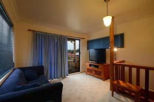 a living room with a couch and a flat screen tv at Seahaven Beach House - Shellharbour in Shellharbour