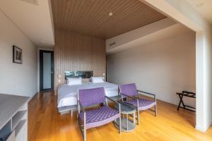 um quarto com uma cama e cadeiras roxas em UMITO the salon IZU em Ito