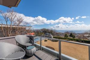 a balcony with chairs and a view of the ocean at UMITO the salon IZU in Ito