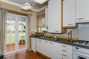 a kitchen with white cabinets and a large window at Burgo Dom Afonso V Golf & Beach Resort in Casal da Lagoa Seca