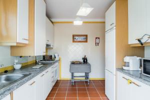 a kitchen with white cabinets and a sink at Burgo Dom Afonso V Golf & Beach Resort in Casal da Lagoa Seca