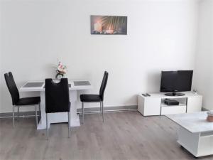 a living room with a white table and a tv at MyHome Basel 1B44 in Saint-Louis
