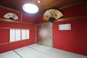 an empty room with red walls and two windows at Maidohaya Fukutatei in Takaoka