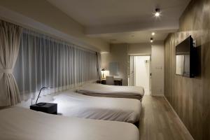 a hotel room with three beds and a window at Shinjuku City Hotel N.U.T.S Tokyo in Tokyo