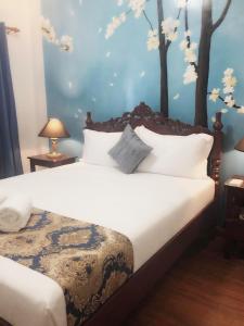 a bedroom with a white bed with trees on the wall at Blue Waters Inn Coron Palawan in Coron